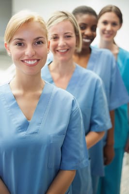 Four healthcare staff members smiling in a hallway
