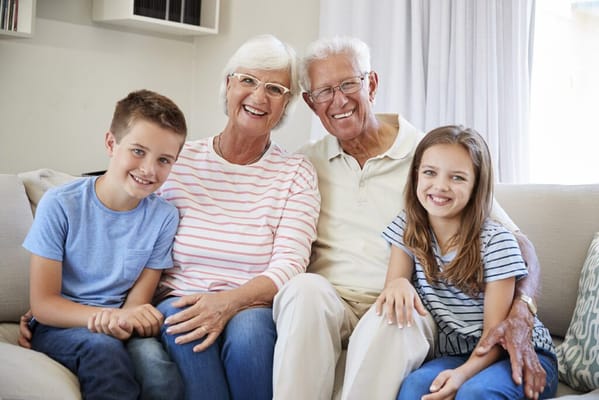 Smiling seniors with their grandchildren on a couch