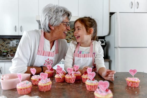 Elderly woman and girl baking cupcakes with heart decorations