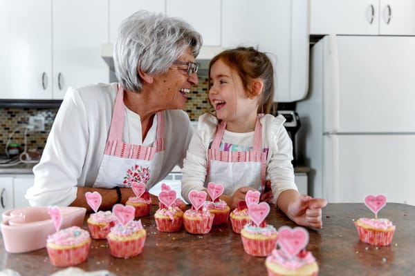 Elderly woman and girl baking cupcakes with heart decorations