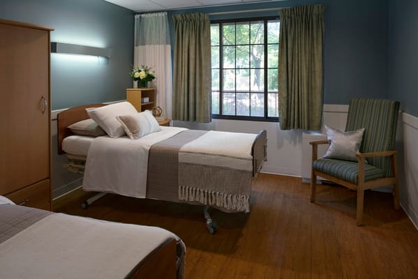 Brightly lit resident room with two beds and a chair