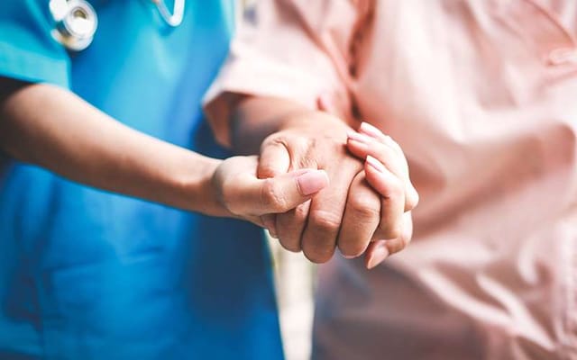 Healthcare worker holding hands with a senior resident