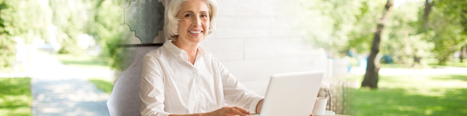 Senior woman using a laptop outdoors in a garden