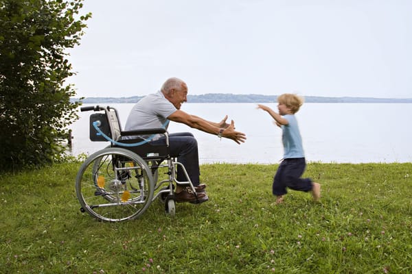 An elderly man in a wheelchair reaching out to a child
