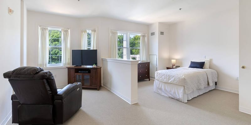 A bright, spacious private resident room with a bed and furniture