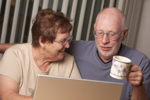 Laughing couple enjoying time together with a laptop