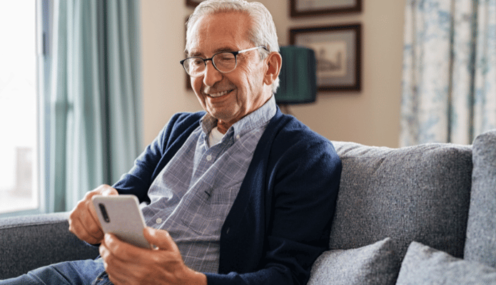 Senior man using a smartphone in a cozy living room