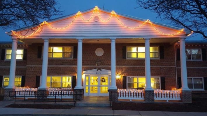 Exterior view of a senior living facility decorated with lights