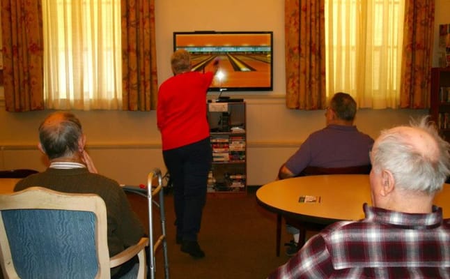 Residents enjoying virtual bowling activity in a common area