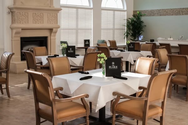 Dining tables with chairs in a cozy restaurant setting at The Blake.