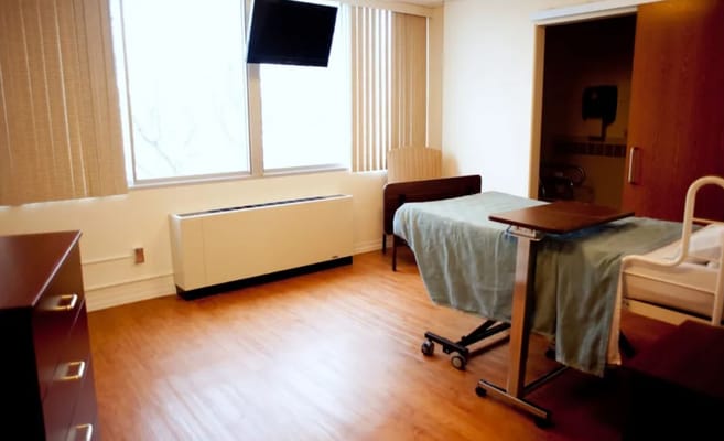 A cozy patient room with a bed and window.