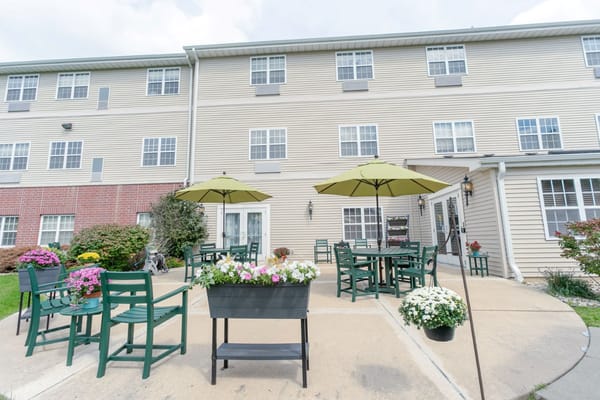 Patio area with green chairs and umbrellas at Heritage Woods of Rockford