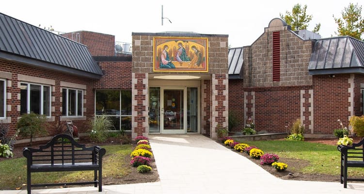 Exterior view of Holy Trinity Nursing and Rehabilitation Center with floral landscaping