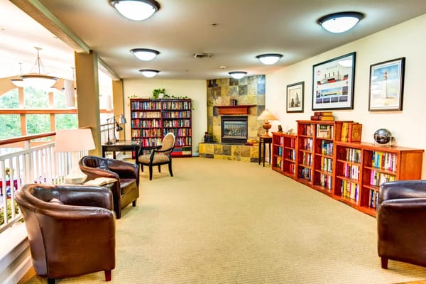 Interior view of the library with bookshelves, seating, and fireplace.