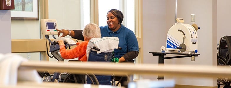 Rehabilitation staff assisting a senior resident during a therapy session