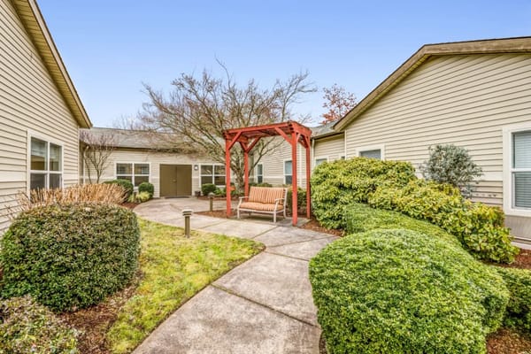 Courtyard with a red pergola and seating area surrounded by greenery