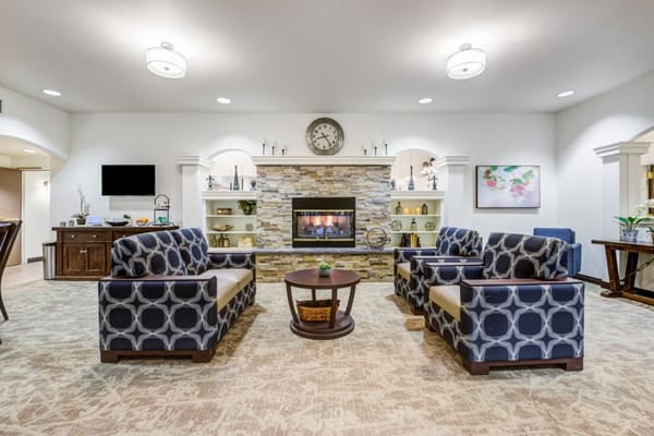 View of a living room with comfortable seating and a stone fireplace