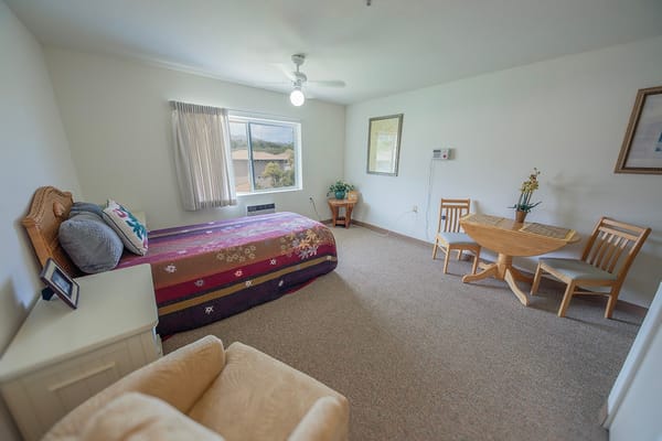 A cozy bedroom with a bed, table, and seating area.