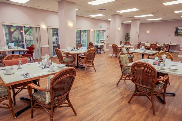 Bright dining area with tables and chairs set for a meal at Roselani Place.