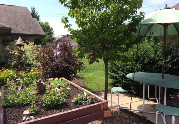 A landscaped garden with flowers, a tree, and outdoor seating
