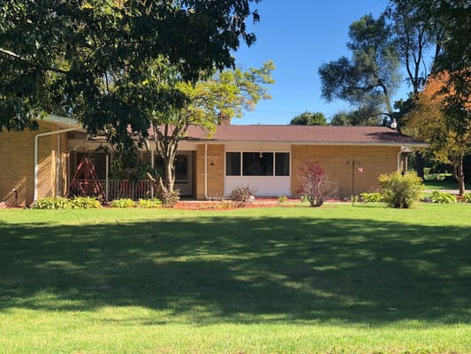 Exterior view of Sugarbush Manor featuring landscaping and a front porch.