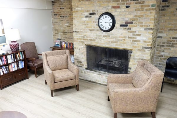Comfortable seating area with two chairs, a clock, and a fireplace