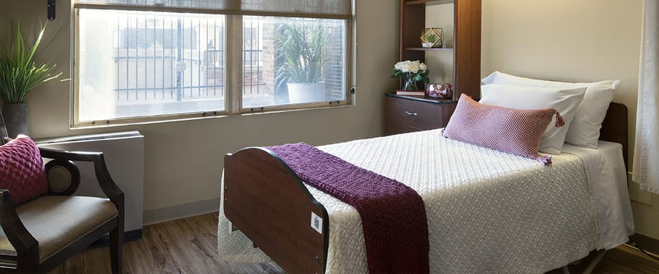 A cozy bedroom with a bed, chair, and window