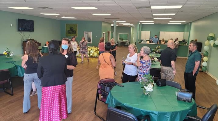People mingling in a common area with green tables and decorations