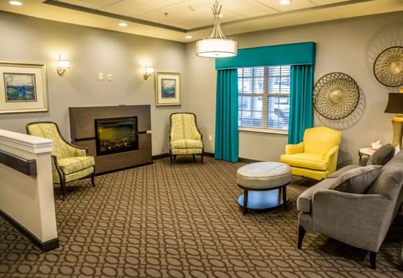 A cozy living room with armchairs, a sofa, and a fireplace