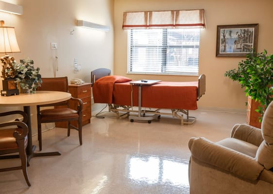 Cozy private room with a bed, table, and armchair.