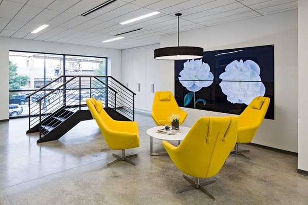 Bright interior common area with yellow chairs and floral artwork