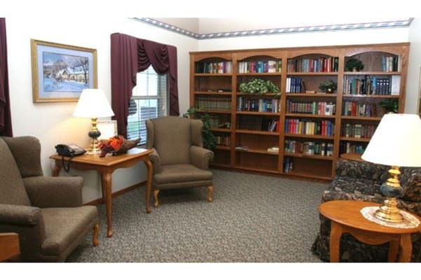 A cozy lounge with seating, a lamp, and a bookshelf.