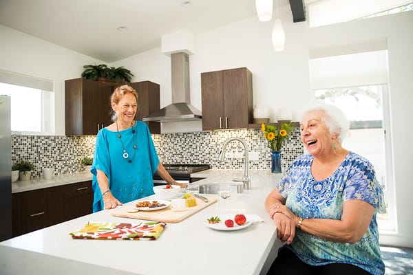 Two residents enjoying time together in a bright kitchen