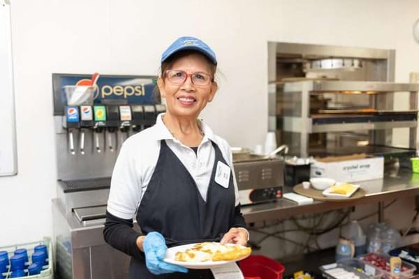 Staff member serving food in the kitchen area