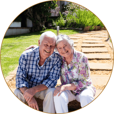 A smiling older couple sitting in a garden