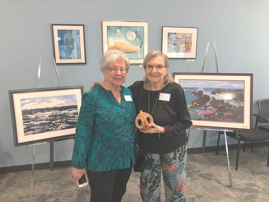 Two residents posing with a decorative item in an art display area.