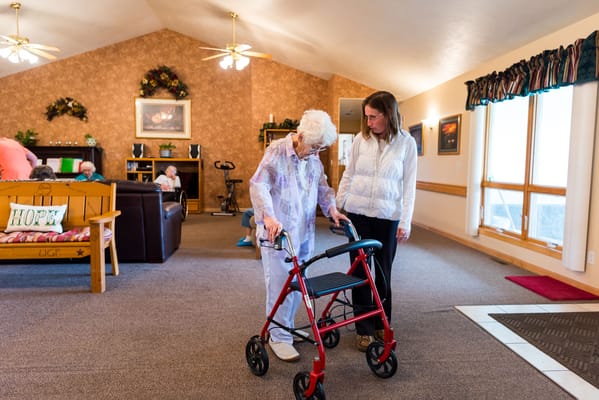 Staff assisting a resident with a walker in a common area