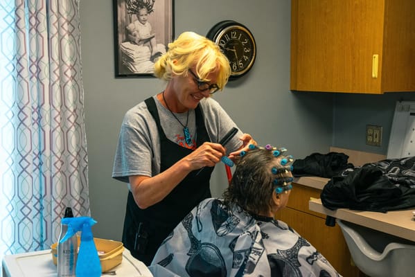Resident receiving a hair treatment from staff