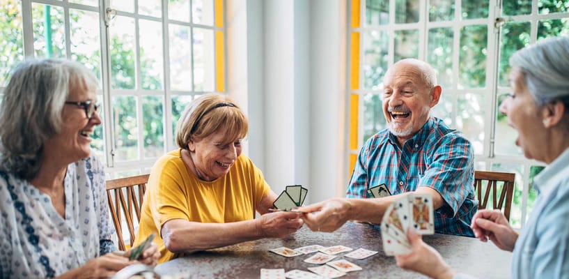 Residents enjoying a card game in a bright activity room