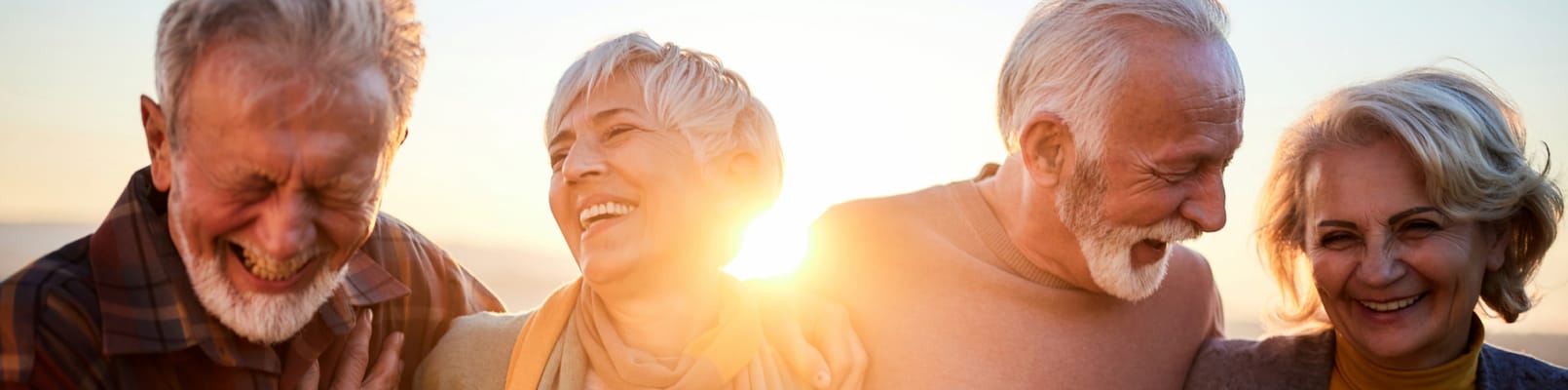 Four seniors laughing together during sunset