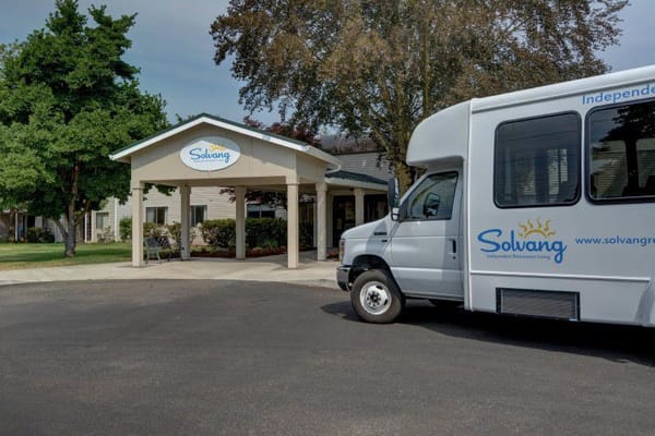 Exterior view of the Solvang Retirement Community building with shuttle bus