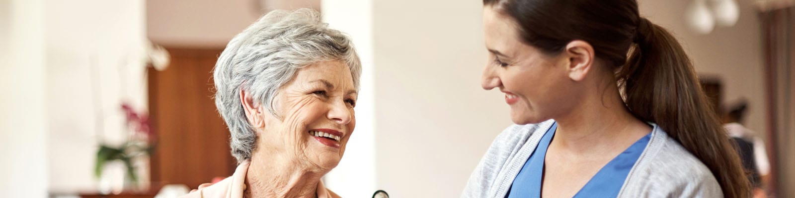 Caregiver smiling with a resident in an indoor setting