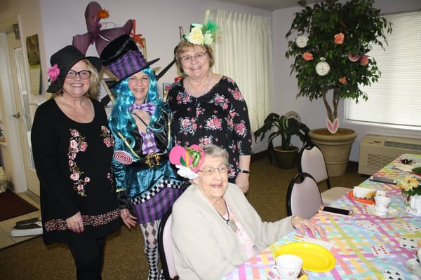 Residents and staff celebrating with festive hats in an interior activity room
