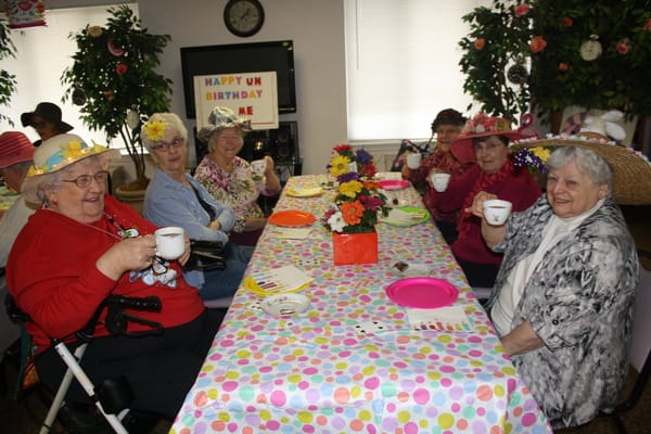 Residents enjoying a birthday celebration with hats and cups