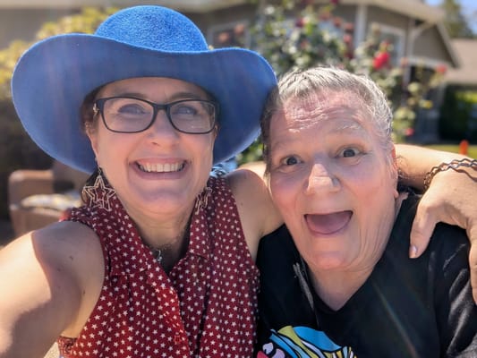Two women smiling together outdoors in a sunny setting