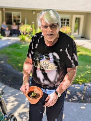 Resident outdoors holding a small potted plant