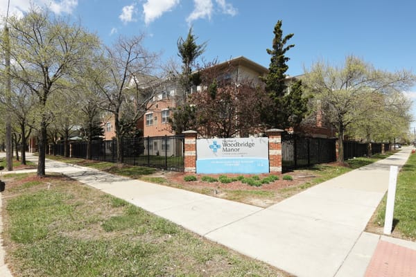 Exterior of Woodbridge Manor with trees and pathway