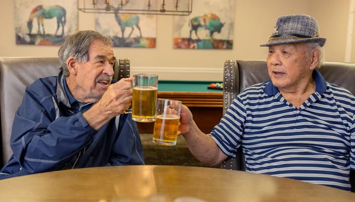 Two residents toasting with beer in a lounge area