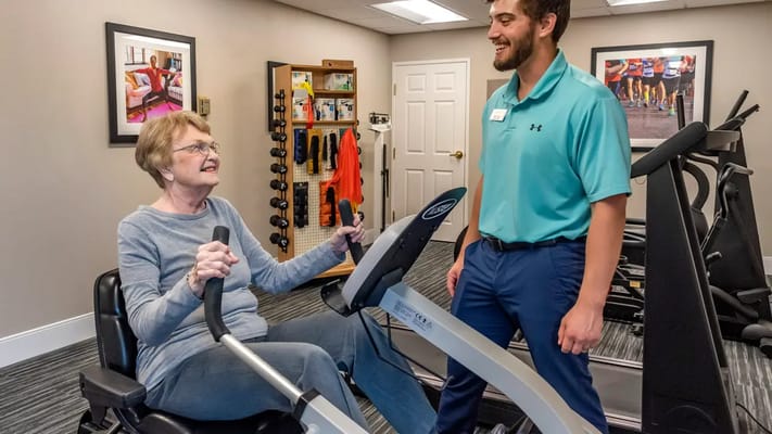 Senior resident exercising with staff assistance