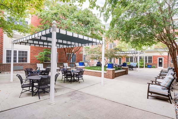 Outdoor seating area with shaded tables and greenery